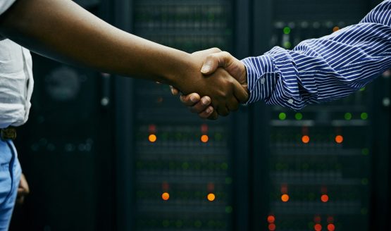 Paired up for professional IT service. Cropped shot of two men shaking hands in a data center.